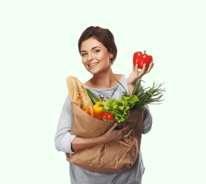A woman holding a bag of food with vegetables in it.