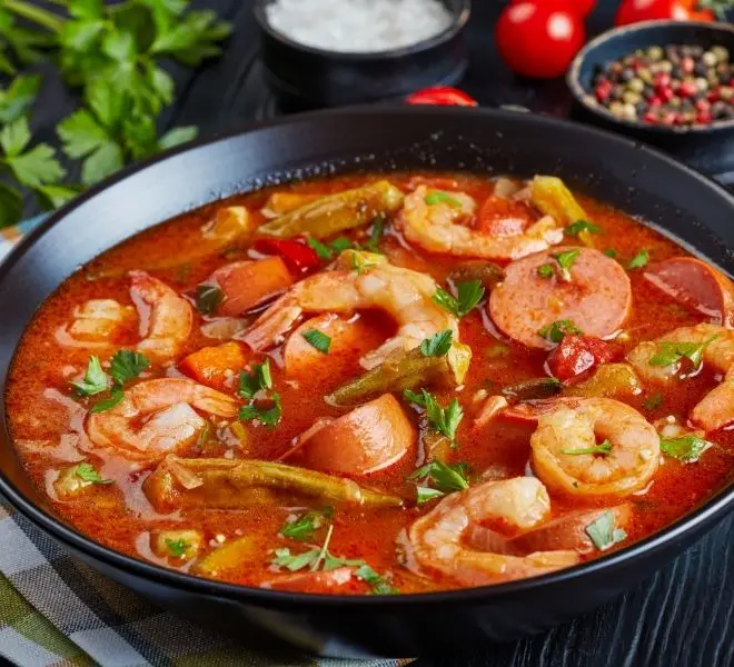 A bowl of shrimp and tomato soup with other ingredients.