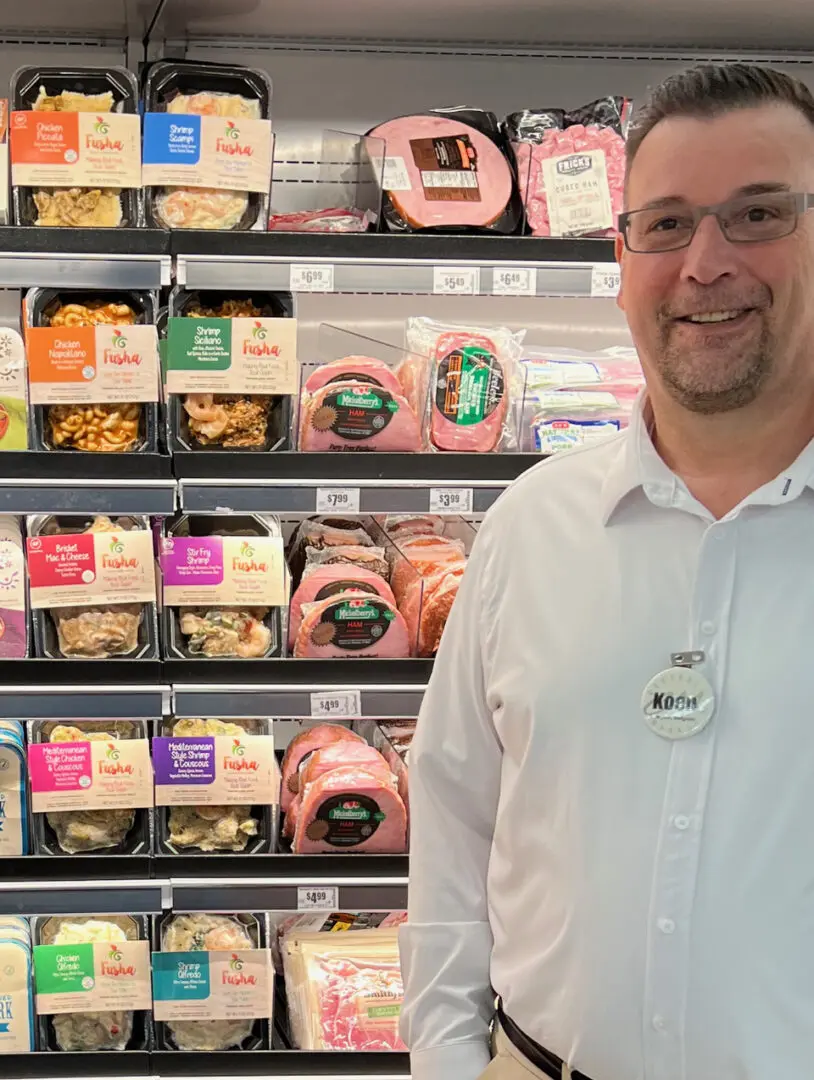 A man standing in front of shelves filled with different types of food.